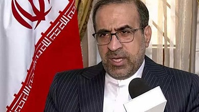Dr Iraj Elahi, former Ambassador of the Islamic Republic of Iran in New Delhi, speaking during an interview with the Iranian flag in the background.