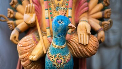 Wooden statue of Hindu god Murugan riding a peacock.