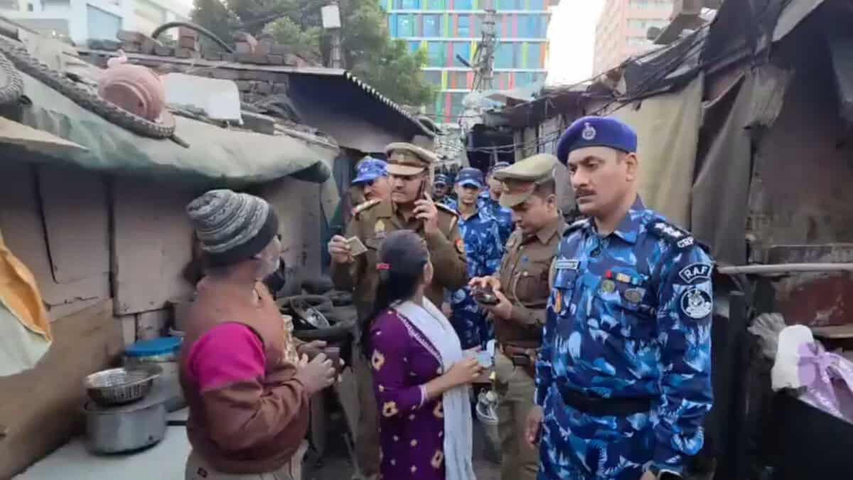 Police officers questions a family residing in a slum area during a citizenship verification drive