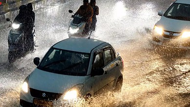 Flooded Hyderabad streets during unseasonal rains with cars and motorbikes in water.