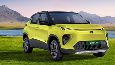 New Tata Punch EV facelift in bright yellow, parked on grass with mountains in background.