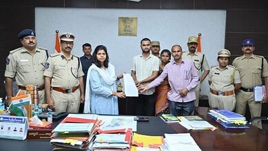 G Soumya with police officers during official document exchange at a formal event.