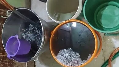 Buckets of polluted water in Warsiguda highlight health risks from contaminated drinking water.