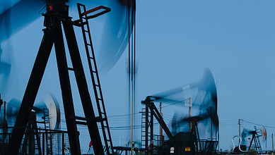 Oil pump jacks at work in an oilfield during daytime.