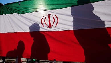 Iranian flag with silhouettes of people at a public gathering.