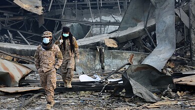 Soldiers inspecting destruction after explosion in urban area.