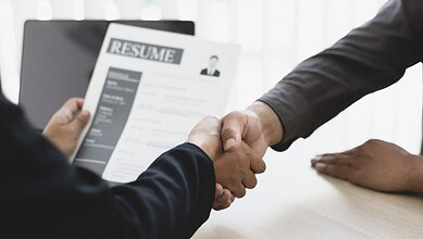 Handshake over a resume during a job interview in an office setting.