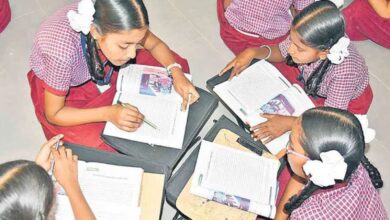 Image shows Young girls in school uniforms studying together on the floor with open textbooks.