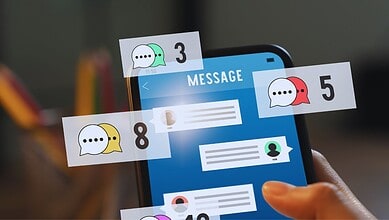 A person holding a smartphone displaying numerous chat alerts, highlighting ongoing suspicious messaging activity linked to Pakistani phone numbers.