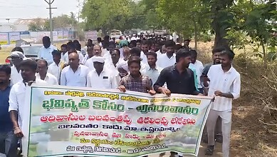 Protesters gather with banners demanding government action for village relocation from tiger reserve area.