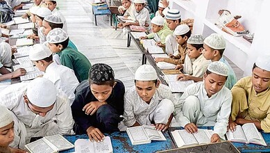 Muslim boys in traditional attire studying religious texts in a madrasa classroom.