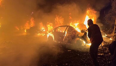 Firefighter extinguishes burning cars after airstrikes in Beirut.