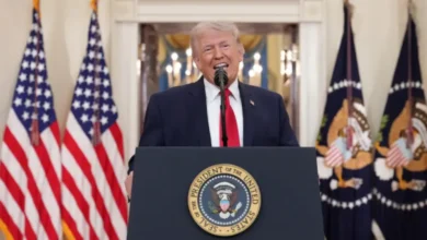 US President Donald Trump delivers a speech at a podium with American flags in the background.