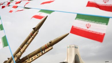 Iranian missiles on display with national flags in the background.