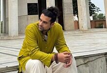 Jubin Nautiyal, the popular singer, sitting outdoors in a yellow kurta, with a contemplative expression,.