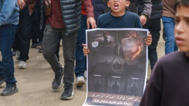 Palestinian boy holds protest poster against Israeli death penalty law in Gaza.