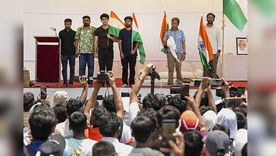 Group of men holding Indian flags on stage during a public event in India.