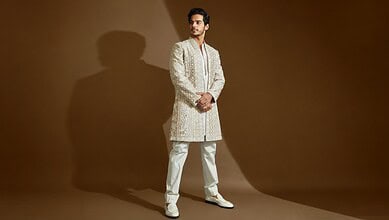 Ishaan Khatter dressed in traditional cream-colored outfit, standing against a brown background.