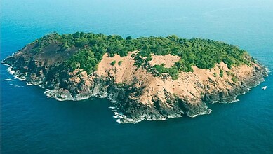 Aerial view of a lush green island with rocky coastlines, surrounded by deep blue ocean waters, showcasin.