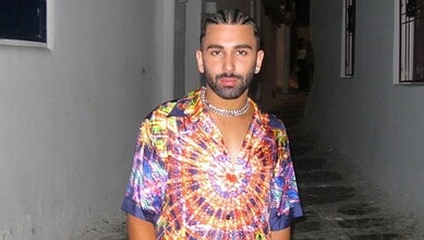 Man with styled hair and beard wearing a vibrant, patterned shirt in a narrow alleyway.