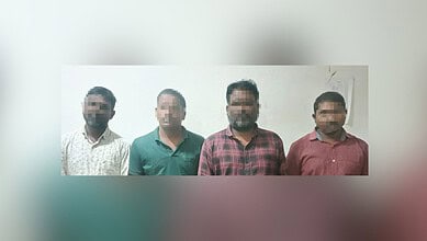 Four men standing against a plain wall, faces pixelated for privacy.