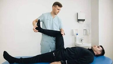 Physiotherapist examining patient's leg in a clinical setting for physiotherapy treatment.
