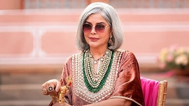 Zeenat Aman with silver hair, sunglasses, and traditional jewelry at an event.