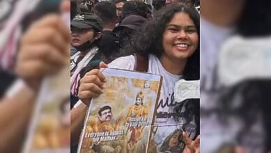 Daughter of Assam minister joins protest, holding a poster with political slogans.