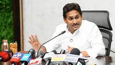 Indian politician addressing media at press conference with microphones and journalists present.