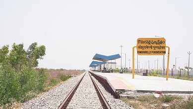 Komuravelli railway station platform with signboard and tracks in rural setting.