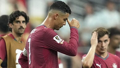 Cristiano Ronaldo in Portugal jersey, looking down with hand on forehead, during FIFA World Cup game.