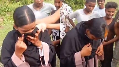 Woman in black saree talking on mobile phone with children around her in Bihar.