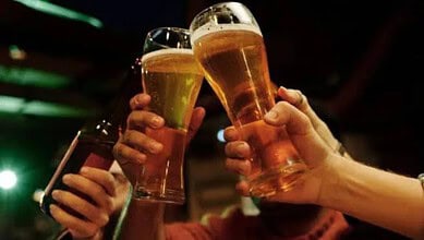 People holding glasses of beer in a social setting at night.
