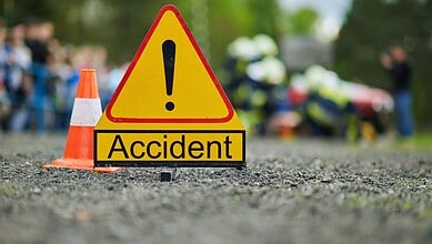 Accident scene with warning sign and blurred emergency responders in background.