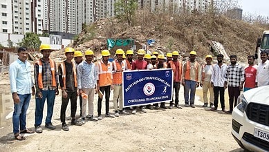 Group of construction workers and officials holding a Hyderabad police banner at a construction site.