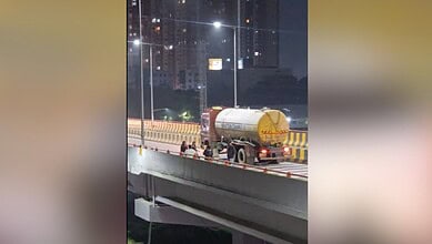 Women dancing on Bachupally flyover at night, with city lights in the background.