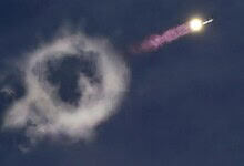 Rocket launch with smoke ring formation in the sky during SpaceX's Starship mission.
