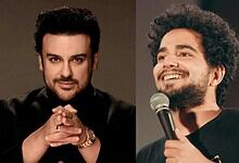 Adnan Sami performing on stage with a microphone, smiling and engaging the audience.