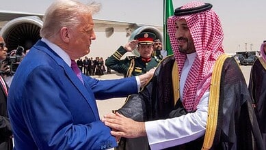 Donald Trump shaking hands with Saudi official during diplomatic visit, military personnel in background.