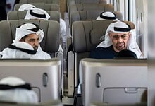Men wearing traditional Emirati attire on a train in Dubai, attending the station opening.