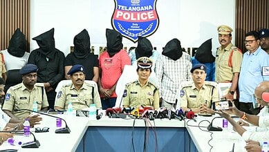 Seven suspects with covered faces and police officers during a press conference in Telangana.