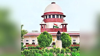 Supreme Court of India building with Indian flag and lush greenery in front.