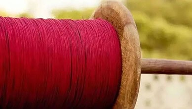 Close-up of a wooden spool with red thread, used for kite flying.