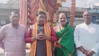 Group of four men standing in front of a large statue during a public event in Basheer Bagh.