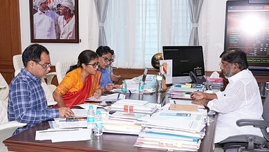 Business meeting with five people discussing documents in a modern office.