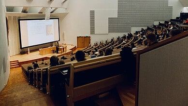 Audience attending a training session in a spacious, modern auditorium with a presenter at the front.