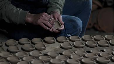 A potter clears oil lamps of dirt before putting them in ove to make them ready to use