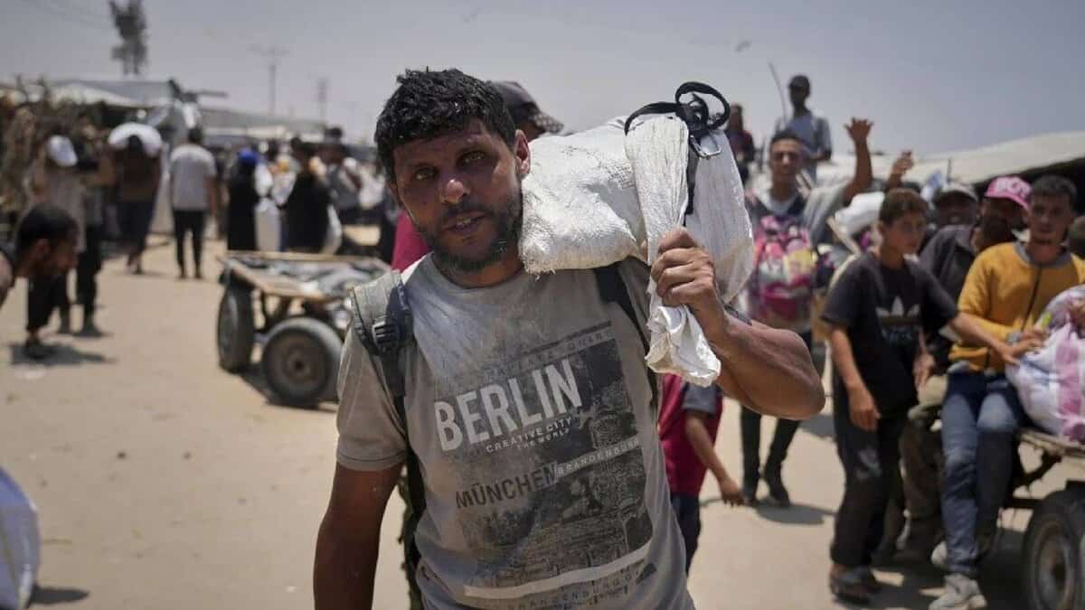 The image of 43-year-old Omar al-Hobi from Rafah carrying a bag of food over his shoulder, wearing a