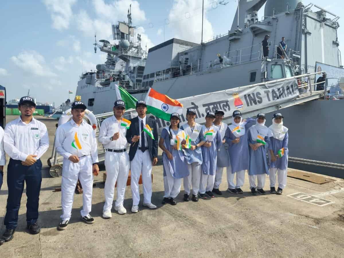 A group of Indian school students and Navy personnel holding Indian flags stand in front of INS Tamal during its port call in Jeddah, Saudi Arabia.