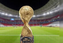 The FIFA Arab Cup trophy displayed on a football pitch inside a brightly lit stadium.